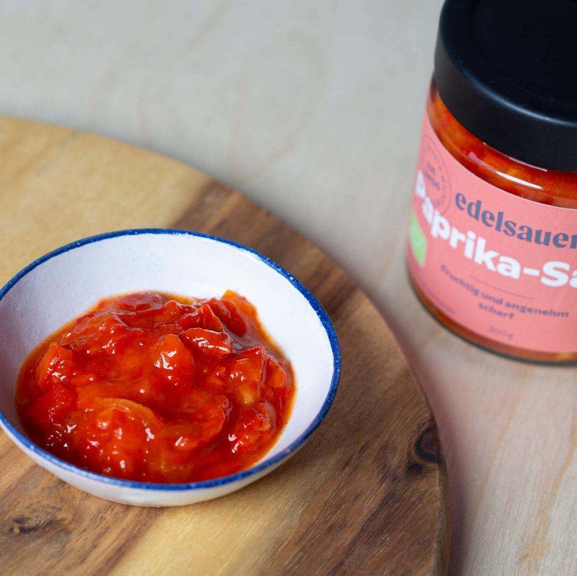 Bio paprika salsa als dip in einer kleinen schale und in der verpackung aus glas von edelsauer